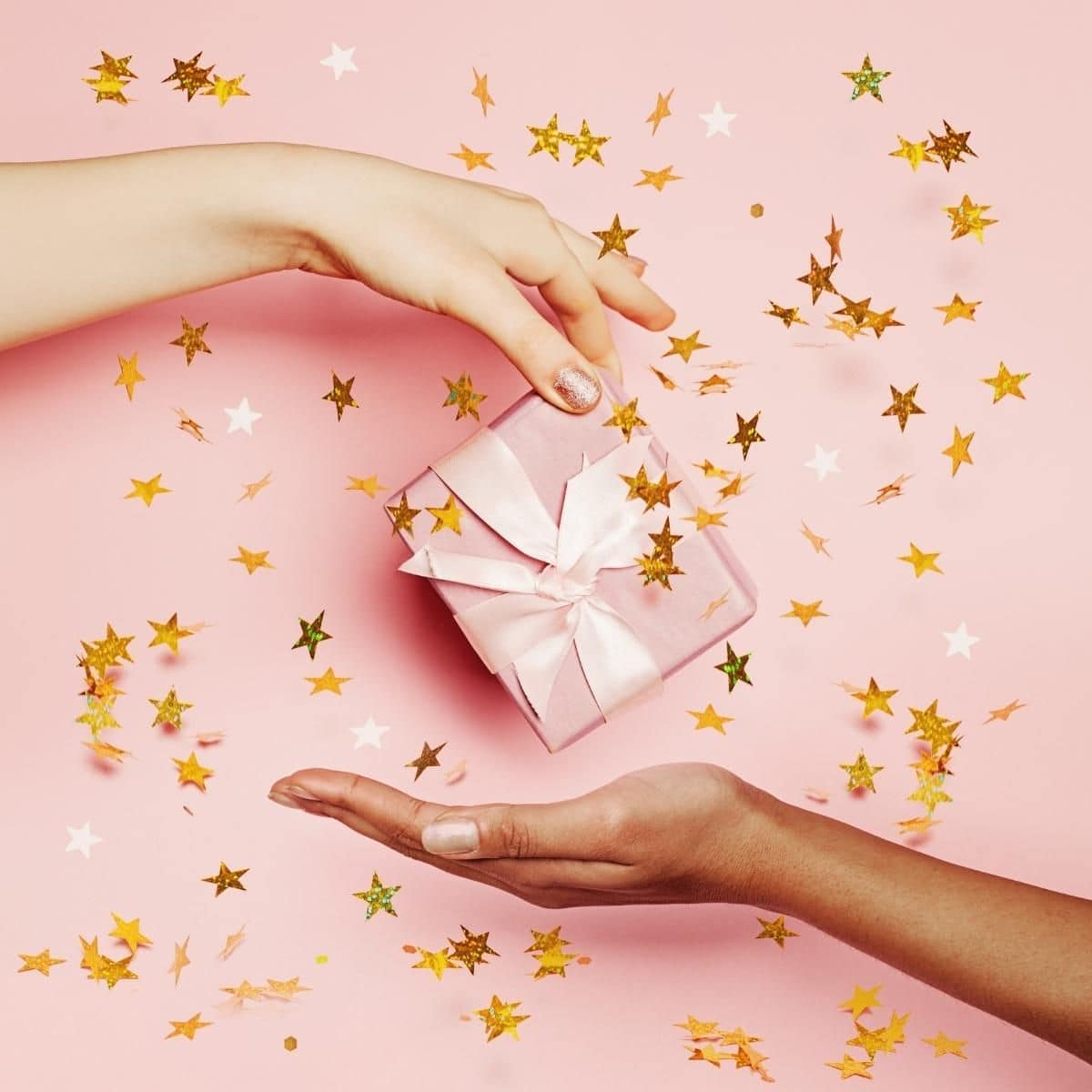 One woman's hand passing a gift to another woman's hand.