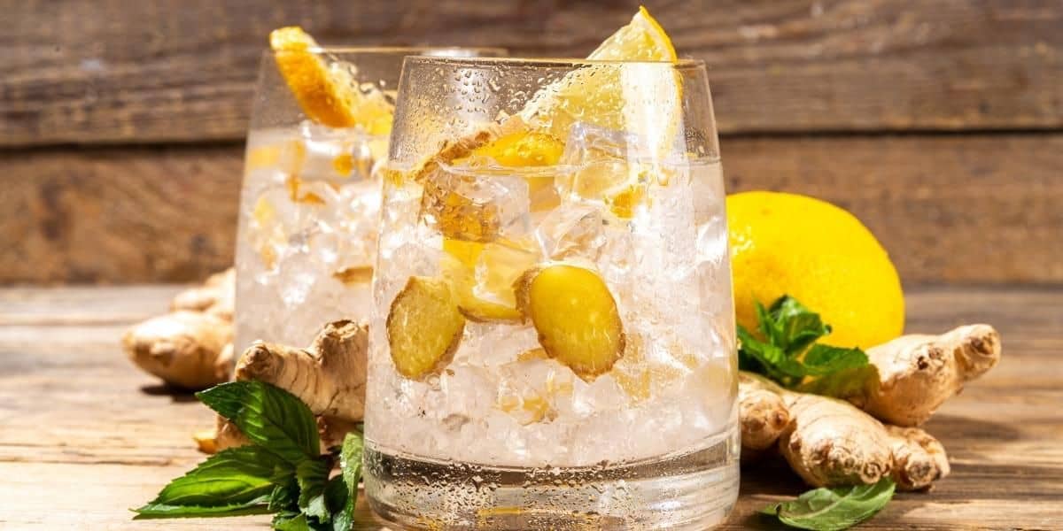two glasses with ice and ginger beverage inside ginger beer and ginger ale
