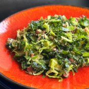 Kale and Brussels Sprout salad on a red plate.