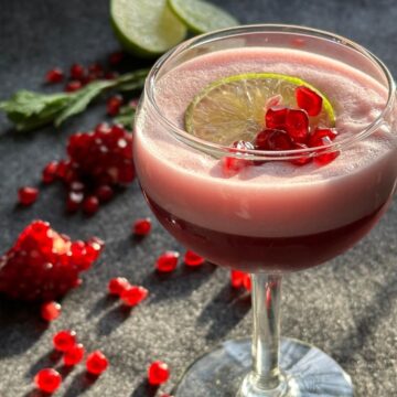 Pomegranate Lime Sour Mocktail garnished with lime slice and pomegranate seeds.