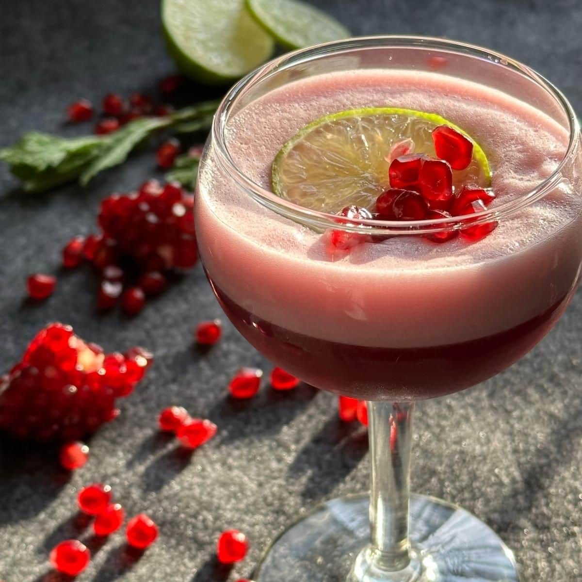 Pomegranate Lime Sour Mocktail garnished with lime slice and pomegranate seeds.
