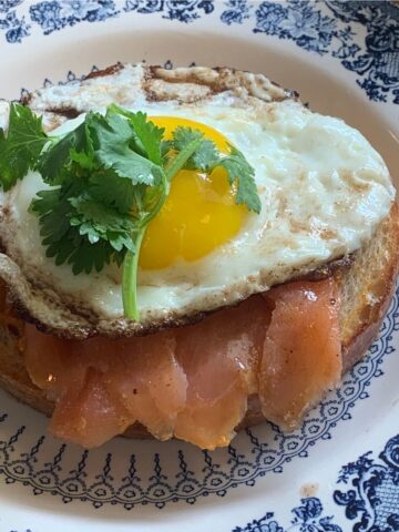 toast with smoked paprika mayo, salmon, and an egg on a blue plate