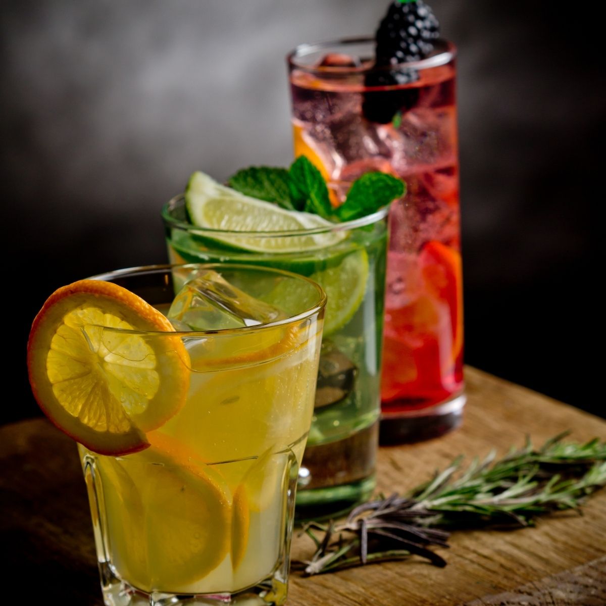 Orange, lime, and berry drinks on a cutting board.