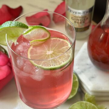Rose lime and ginger beer drink in a glass with lime garnish on a marble surface.