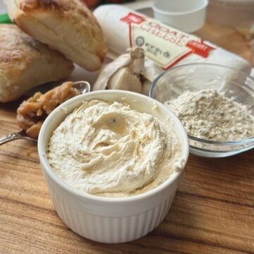 Roasted garlic and goat cheese spread and ingredients on a cutting board.
