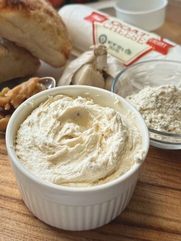 Roasted garlic and goat cheese spread and ingredients on a cutting board.