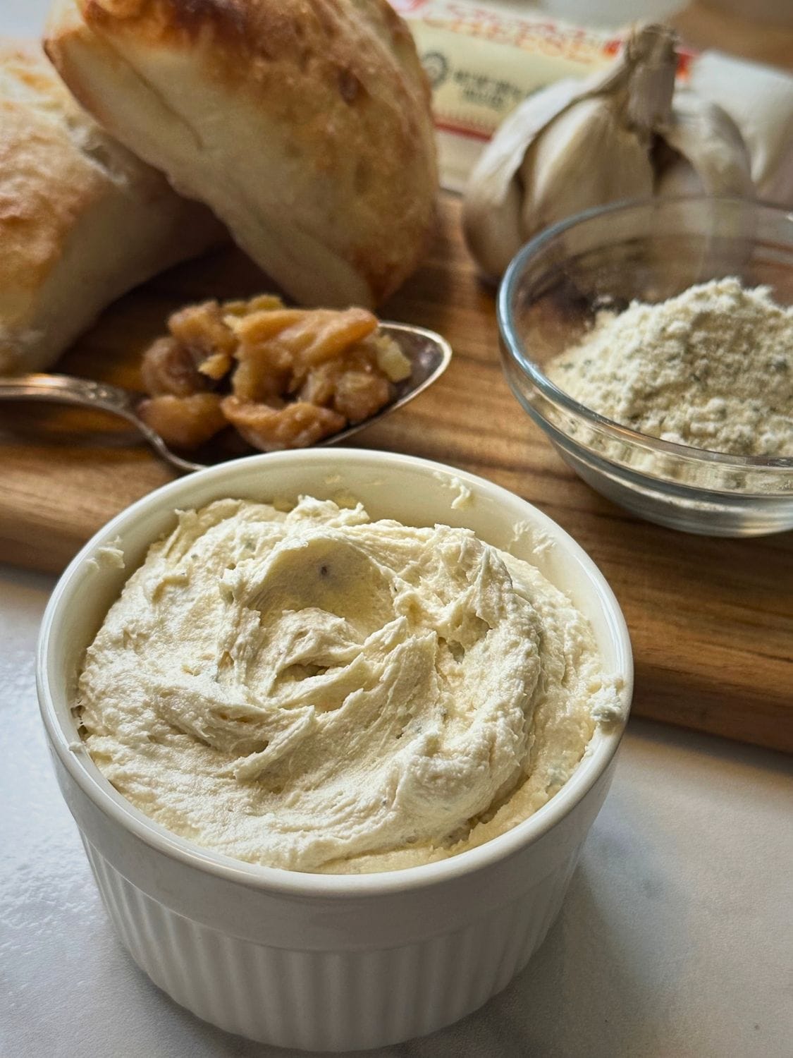 Roasted garlic and goat cheese spread and ingredients on a cutting board.