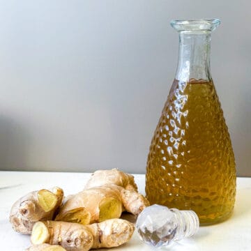 fresh ginger and ginger syrup in a bottle on a table
