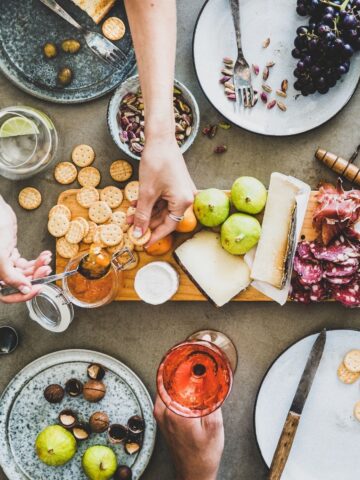 woman taking a cracker and jam from a charcuterie board.