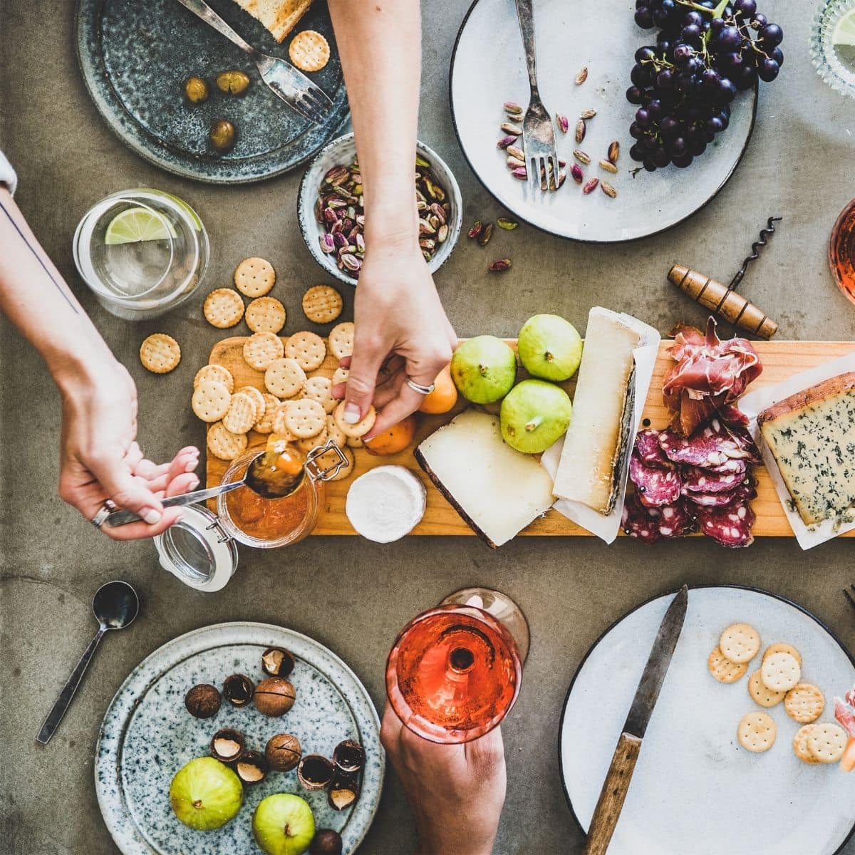 woman taking a cracker and jam from a charcuterie board.