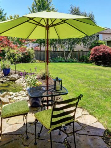 Wrought Iron chairs and table on a stone patio with a green umbrella