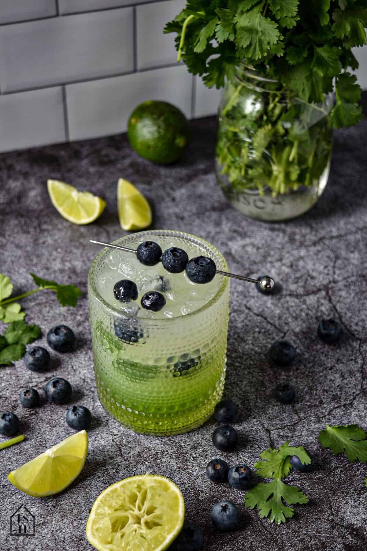 Cilantro limeade garnished with blue berries on a gray background.