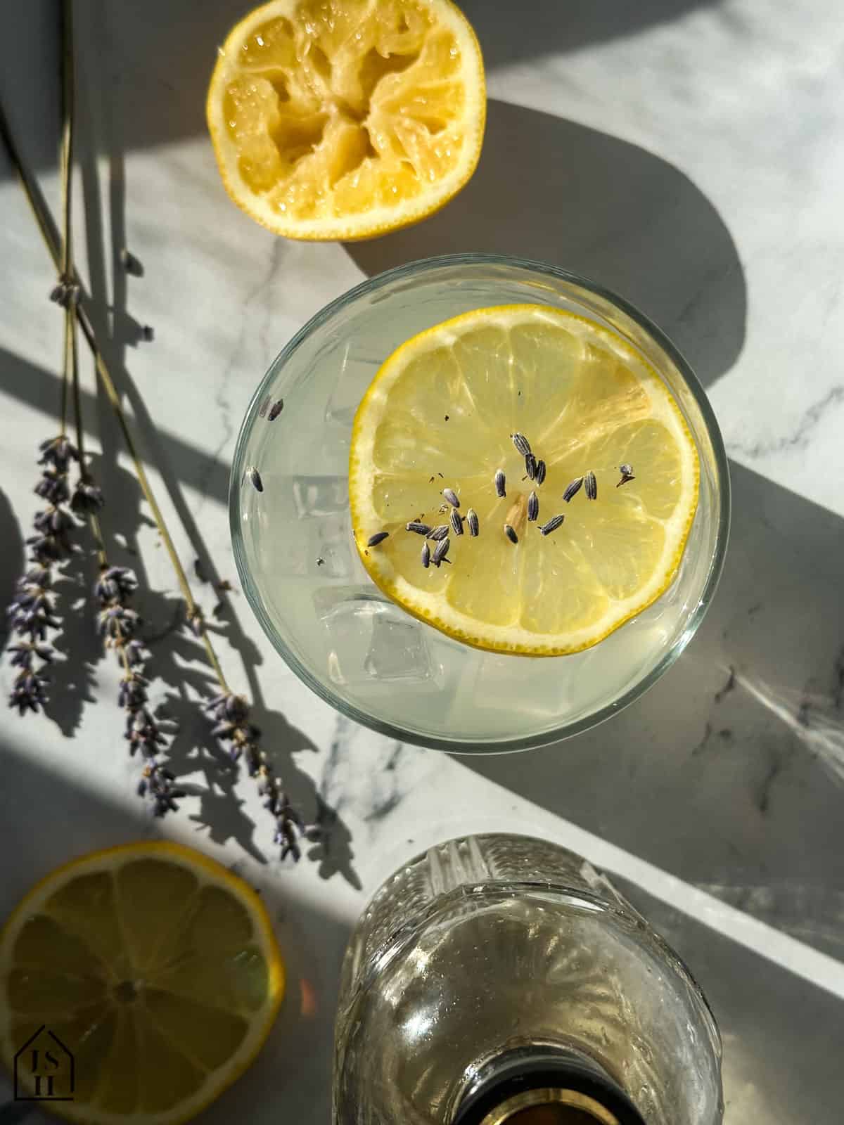 Lavender Lemonade in a glass next to lavender stems and lemon slices.