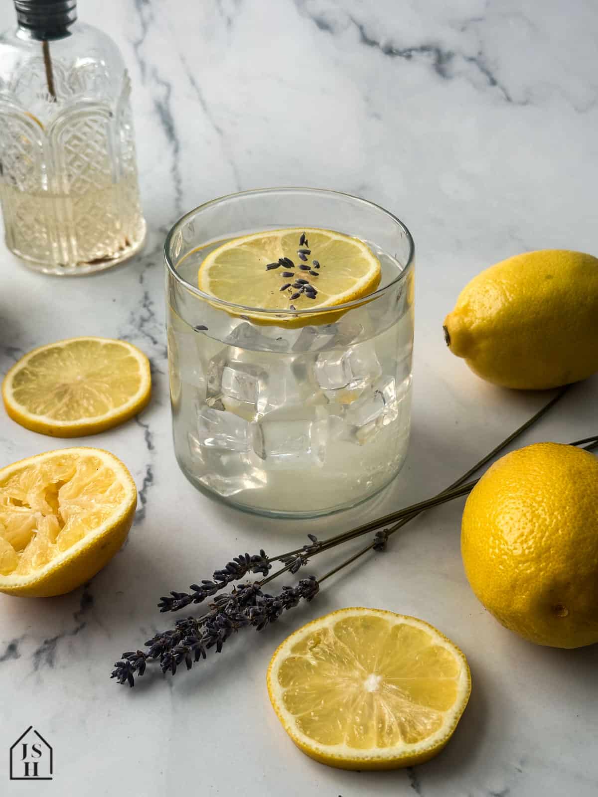 Lavender Lemonade in a glass next to lavender stems and lemon slices.